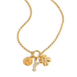 Close-up of gold layered necklace with clover, diamond letter, and queen coin pendants