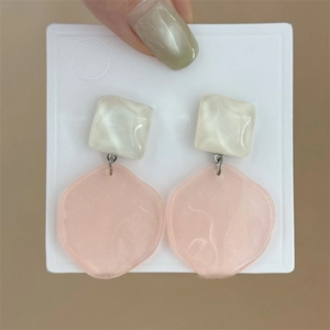 Nahaufnahme der Harzohrringe in Crème und Rosa mit unregelmäßiger Rautenwellenform