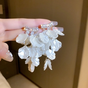 Detail of elegant pearl petal tassel earrings with sparkling crystals held in hand