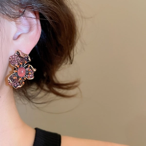 Détail de boucle d'oreille fleur vintage avec strass roses et pétales en métal doré