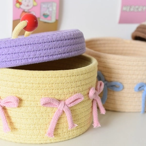 Close-up of hand-woven cotton storage baskets with decorative bows and colorful lids