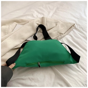 Close-up of neon green nylon crossbody bag with adjustable black strap on casual clothing