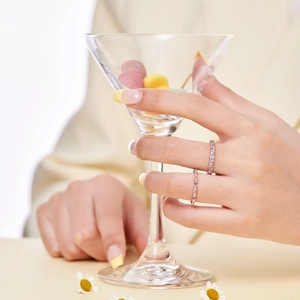Close-up of slender S925 silver rings with multi-color zircon inlay on a glass rim
