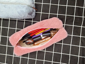 Detailed interior of plush pink pencil case filled with stationery and cosmetics