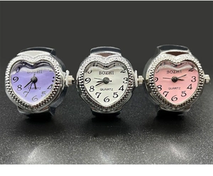 Detailed view of heart-shaped ring watches with sparkling crystal bezels in three colors