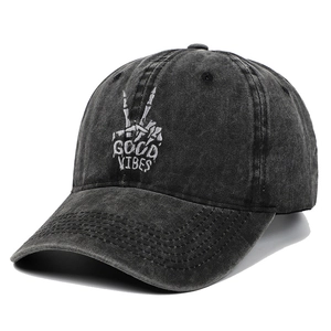 Close-up of skeleton hand and Good Vibes embroidery on washed black cotton baseball cap