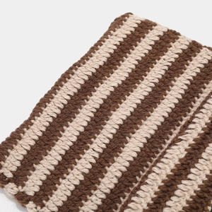 Close-up of handmade coffee and cream striped knit fabric texture on devil cat ear hat
