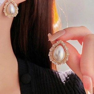 Elegant gold drop pearl earrings with micro-p鑲 zircon stones on a model's ear