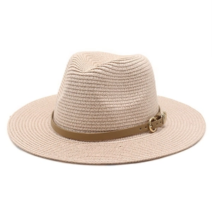 Gros plan d'un chapeau de paille beige clair avec bande en cuir brun et boucle dorée