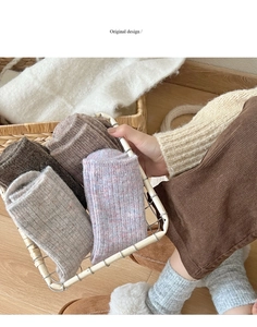 Close-up of thick ribbed knit wool socks in earthy tones inside a metal basket