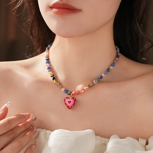 Close-up of a colorful beaded necklace with a red and pink polka dot heart pendant