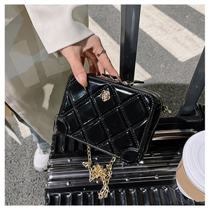 Detail of black PVC jelly bag with quilted pattern, gold flower accent and chain strap