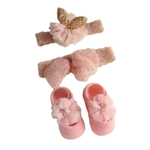 Pink baby headband and socks set with lace bow, sequins, and knit details on white background