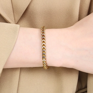 Detailed close-up of two-tone V-shaped stainless steel wheat chain bracelet on wrist