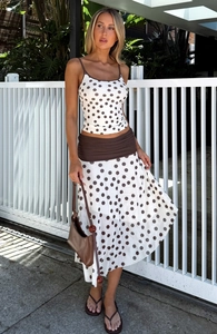 Detail of white polka dot crop top and maxi skirt with a brown pleated waist belt