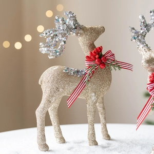 Golden Christmas reindeer figurine with red bow on snow base with festive bokeh lights