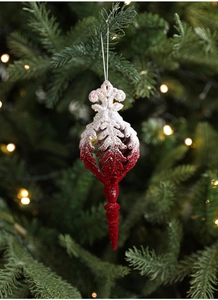 Detail of red and white flocked Christmas ornament with glitter hanging on a tree