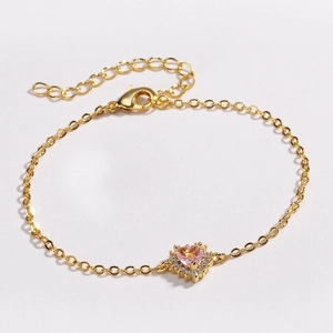 Détail du bracelet avec pierre précieuse en forme de cœur rose et chaîne en or pavée
