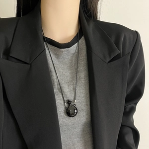 Minimalist silver perfume bottle necklace with a glossy black circular pendant on a long cord
