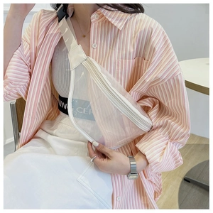 Close-up of clear PVC crossbody chest bag with white trim on casual striped outfit