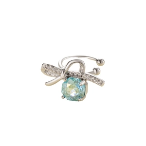 Silver bow ear cuff with clear crystals and a hanging blue faceted gemstone on white background