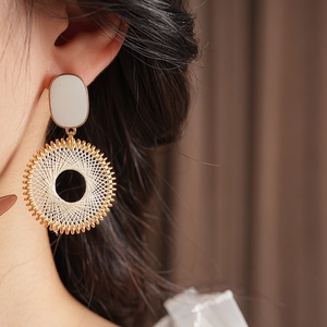 Close-up of woven grid pattern hoop earring with gold finish on a model