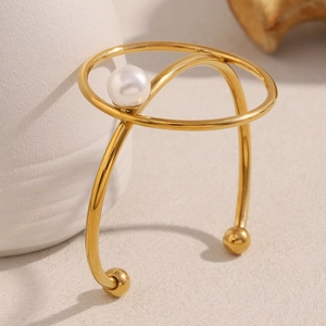 Macro view of gold-plated knot bracelet featuring a large white pearl on stone background