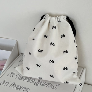 Detail view of cream drawstring pouch with black bow prints on elegant gift box