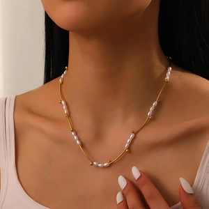 Close-up of gold-plated stainless steel tube and pearl choker on model's neckline