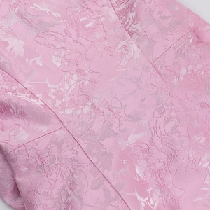 Vue détaillée du tissu jacquard rose avec motif floral élégant pour cette robe