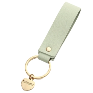 Light green leather keychain with golden heart charm engraved HE IS LOVE on white background
