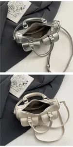 Detailed view of saddle handbags in metallic silver and off-white with double front pockets