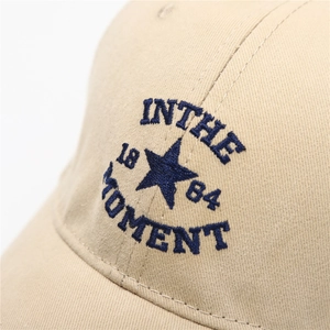 Close-up of blue embroidery on khaki cotton baseball cap showing detailed texture