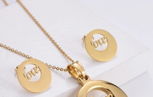 Macro view of gold plated titanium steel jewelry set with hollow LOVE round pendants