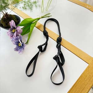 Detail of adjustable black nylon webbing strap with plastic buckles on a white desk