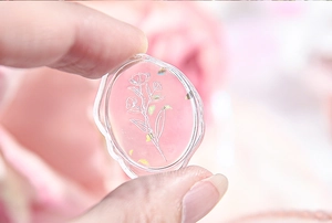 Detail of transparent resin wax seal sticker with white floral patterns and sparkles