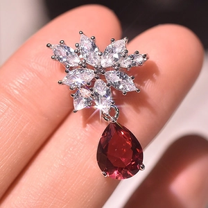 Detailed close-up of a silver snowflake earring with a large red pear-cut zircon stone