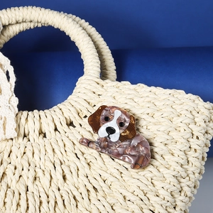Fashionable brown and white marbled acrylic dog hair clip on a woven straw bag accessory