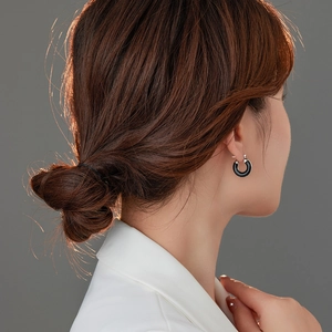 Dettaglio dell'orecchino a cerchio in smalto nero indossato per un look minimalista
