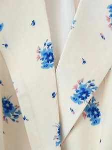 Dettaglio del classico bavero con stampa floreale blu su trama di tessuto bianco crema