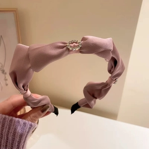 Dettaglio del cerchietto in raso rosa con decorazione di anello in strass scintillanti