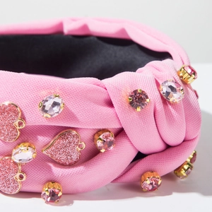 Detailaufnahme des rosa Stoff-Stirnbands mit Kristallperlen und glitzernden Herzanhängern