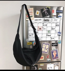 Detailed view of black nylon crescent bag with adjustable strap on a decorated background