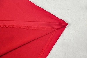 Detailed macro shot of fine double-needle stitching on red slim fit knitted fabric