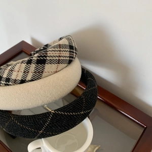 Retro plaid and solid color padded headbands stacked on glass for a vintage college style