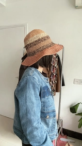 Detail of hand-woven striped straw sun hat featuring beige, coffee, and brick red gradients