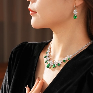 Détail macro du collier et des boucles d'oreilles argentés avec zircons en goutte émeraude
