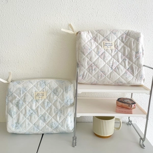 Detailed view of quilted cotton floral cosmetic bags on a white shelf with accessories