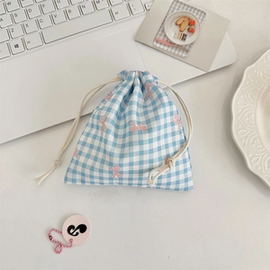 Blue and white checkered drawstring storage bag with pink bow pattern on a desk