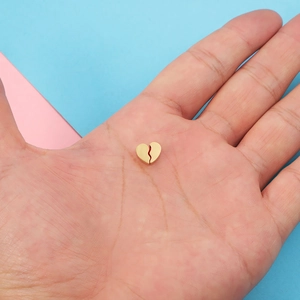 Golden stainless steel broken heart charms held in hand for jewelry making diy